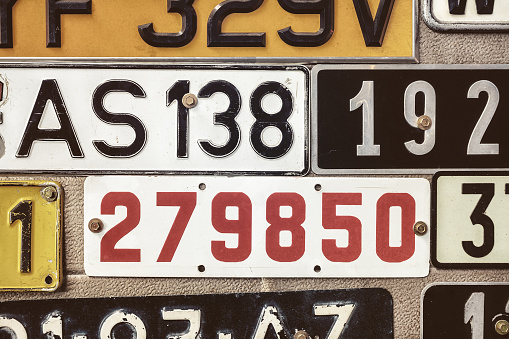 Sepia toned image of old number plates on a metal garage door