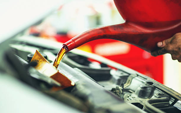 Replacing engine oil. Closeup of unrecognizable mechanic pouring fresh oil out of red oil canister into car engine. He had previously disposed off the used oil. Engine oil filter is always replaced along with the oil unless you're just adding some fresh to your engine. viscose stock pictures, royalty-free photos & images