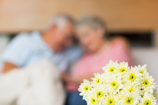 Bouquet of fresh flower with senior couple in background at home