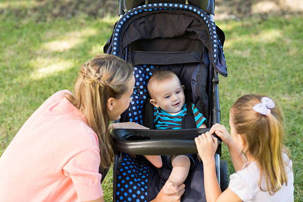 Young smiling mother pushing her small boy in a stroller in blurred motion.