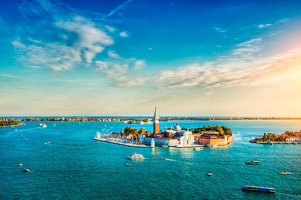 Aerial view of the lagoon of Venice and San Giorgio Maggiore at Sunset. Heavy ship traffic, turistic boats and beautiful blue sky with fantastic cloudscape over the island. Venice, Italy.