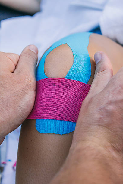 istock Physiotherapist putting a  kinesiotape strip on a knee 493328402