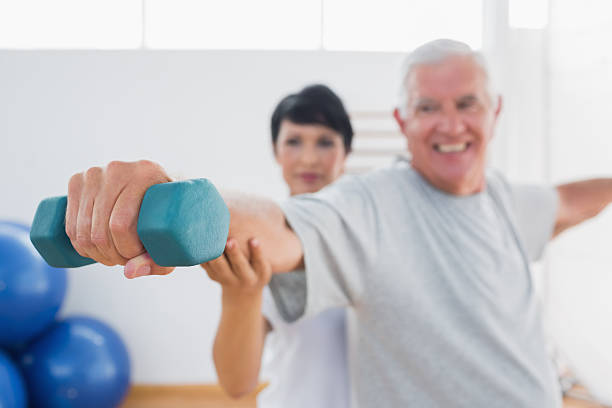 istock Trainer assisting senior man at gym 493373343