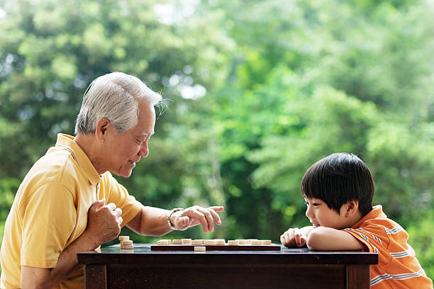 abuelo y nieto jugando xiangqi (ajedrez chino) - concentration chess playing playful fotografías e imágenes de stock