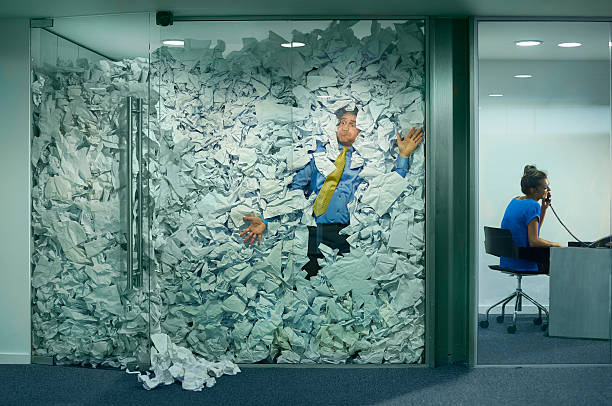 stuck at the office A businessman is trapped in his glass office by a surplus of discarded ideas on paper . His colleague in the next office is working more efficiently and is oblivious to him being trapped . stuck stock pictures, royalty-free photos & images