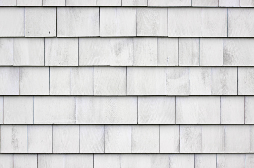 Close view of a wall that has whitewashed wood shingles.