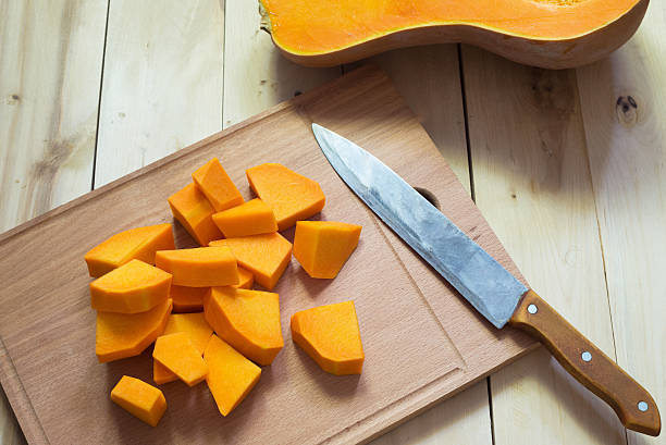 istock Sliced raw orange pumpkin on wooden cutting board 493375404