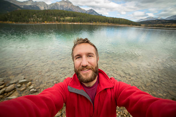istock Young man by the lake taking a selfie portrait. 493377268