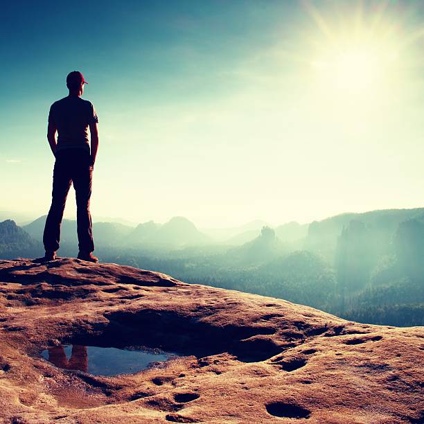 istock Alone man in cap on peak of rock. Beautiful moment 493379886