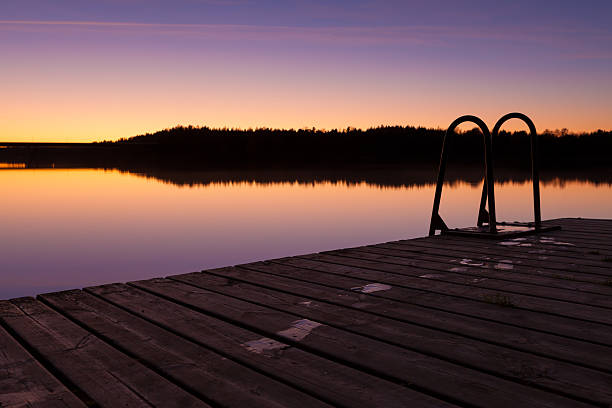 Night swim dock and calm lake at twilight with wet footprints