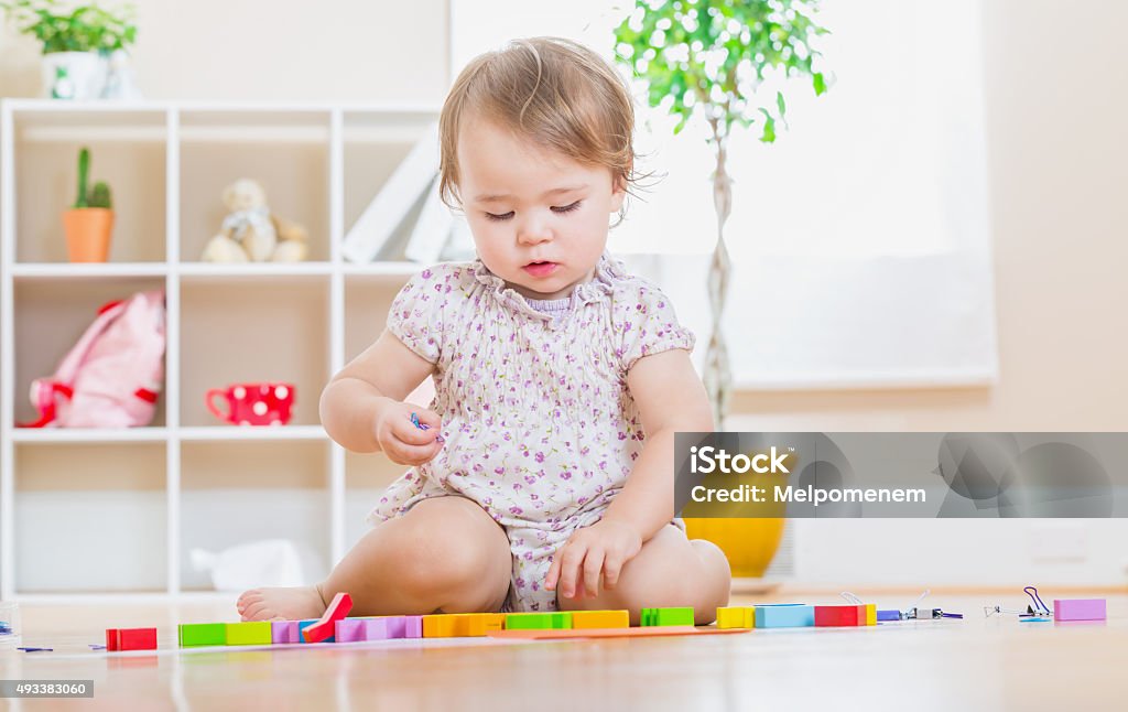 Toddler girl playing her toys Happy toddler girl playing with her wooden toy blocks 12-17 Months Stock Photo