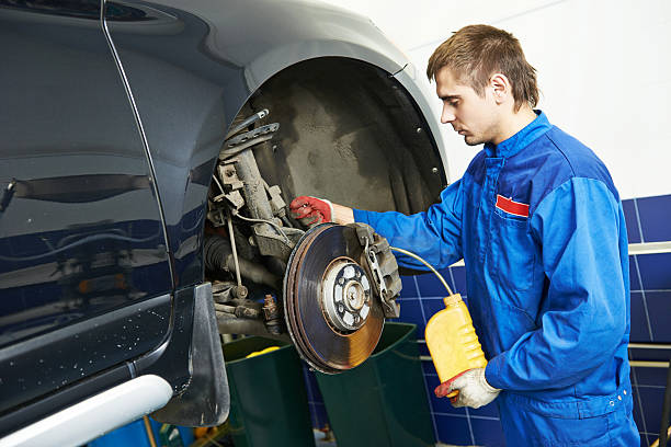 Automobile brake liquid replacing Auto service. car mechanic worker replacing brake liquid of lifted automobile at repair garage shop station brake stock pictures, royalty-free photos & images
