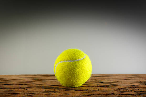 New yellow tennis balls on a wooden table. In light and shadow. Copy space room text.