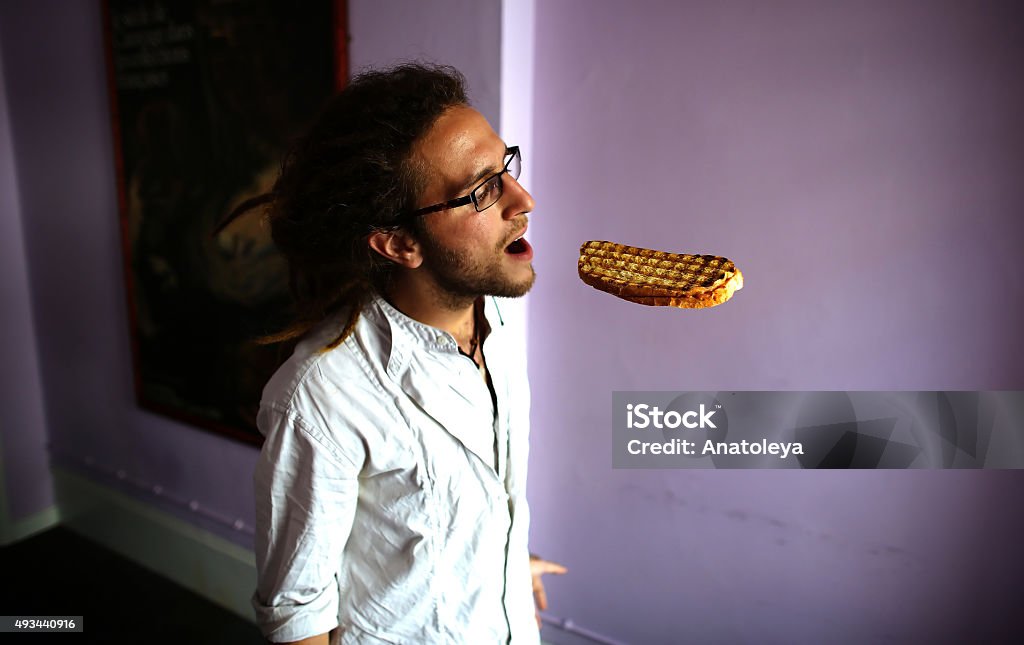 Hungry man eating biting floating sandwich Young man opening his mouth to take a bite from a floating sandwich. Eating Stock Photo