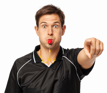 Portrait of angry soccer referee whistling while pointing against white background. Horizontal shot.