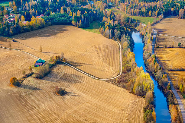 Aerial Photo of a rural farm, winding road and river during Autumn in Finland, shot from an airplane.