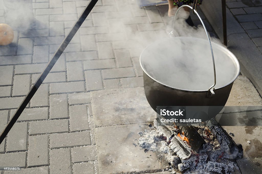 pot with food on metal rods vaporize on fire large antique old pot on metal rods strongly vaporize on fire outdoors Activity Stock Photo