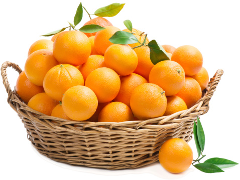 Orange fruits with green leaves in basket with one on the surface in the foreground, isolated on a white background