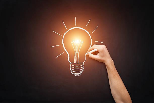 Big idea Human hand drawing light bulb on blackboard. big idea stock pictures, royalty-free photos & images