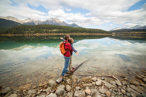 istock Young couple balances on tree log above lake 493472018
