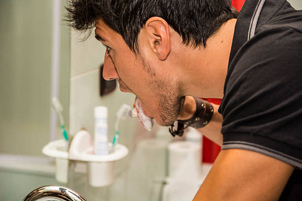 photo de séduisante jeune homme se brosser les dents et de la languette - smiling human teeth toothbrush moving up photos et images de collection