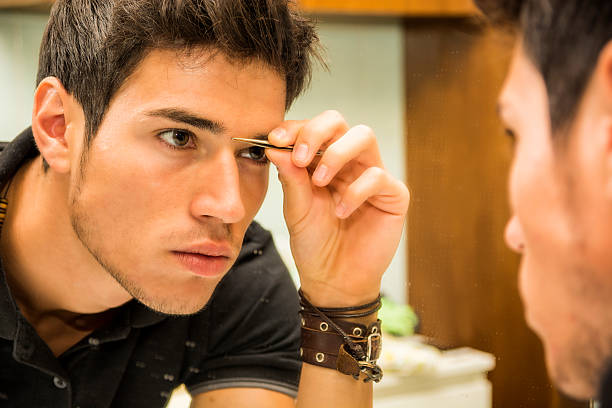 istock Reflection of Young Man Plucking Eyebrow Hairs 493474496