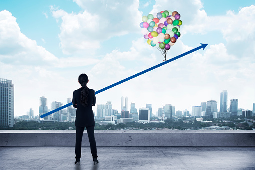 Asian business woman looking arrow up with baloon on the city