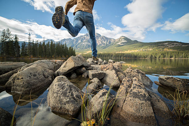 istock Hiker jumps rock to rock in mountain lake 493480048