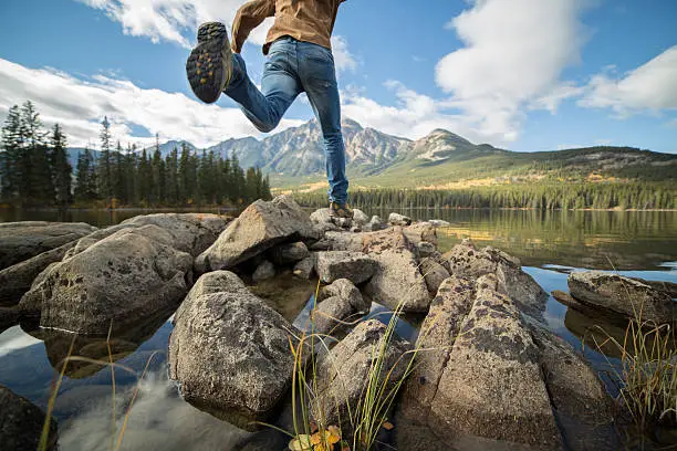 Photo of Hiker jumps rock to rock in mountain lake