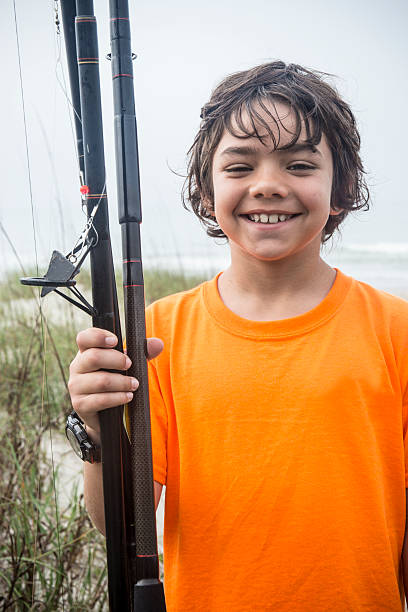 istock Happy boy with fishing rods on a beach 493499031
