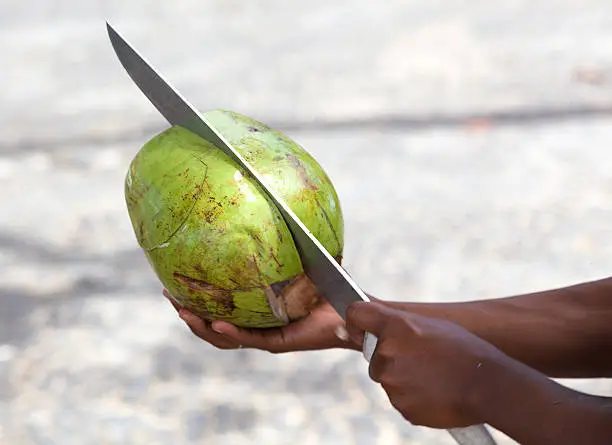Woman cutting coconut at beach Vitoria