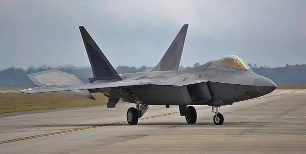 Head-on view of an F-22 fighter jet taxiing down the runway.