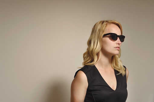 Caucasian blonde wearing a black summer dress combined with black sunglasses.