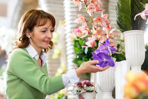 Mature woman looking at orchids in a flower shop.