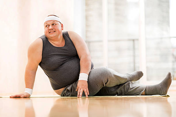 istock Smiling fat man stretching on the floor. 493507070