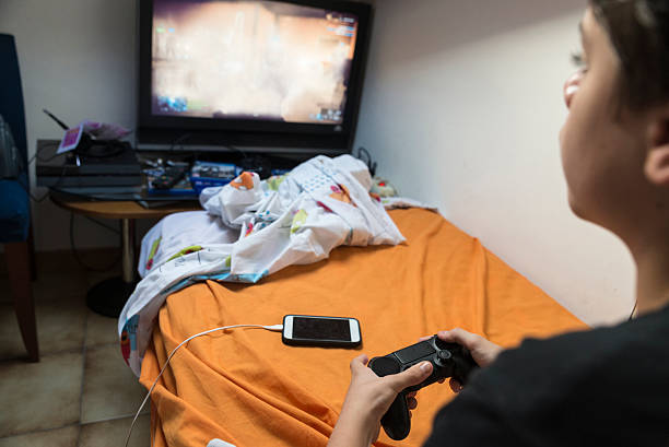 niño jugando juegos de video en casa - video game child handheld video game little boys fotografías e imágenes de stock