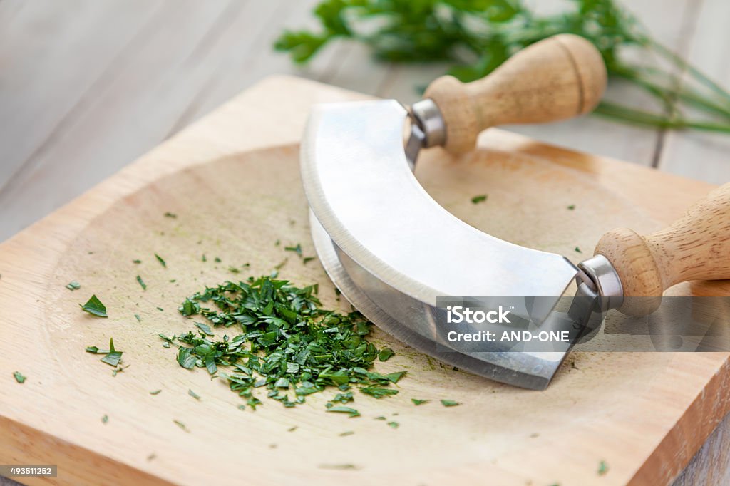 Fresh parsley on a board with mezzaluna Freshly chopped parsley on a board with mezzaluna 2015 Stock Photo