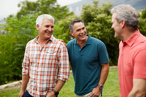 happy mature friends enjoying in park - 中年の男性 ストックフォトと画像