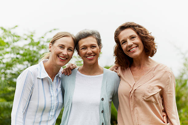 happy mature women standing in park - three people fotografías e imágenes de stock