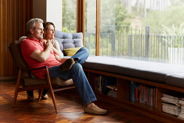 Thoughtful mature couple at home Thoughtful mature couple relaxing by window at home grey hair on floor stock pictures, royalty-free photos & images