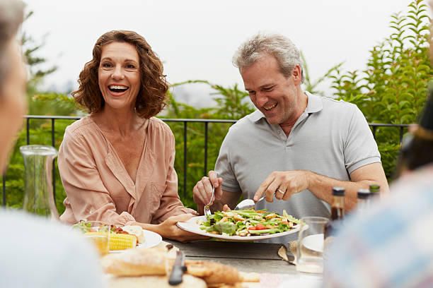 couple enjoying outdoor lunch with friends - mature adult couple caucasian outdoors fotografías e imágenes de stock