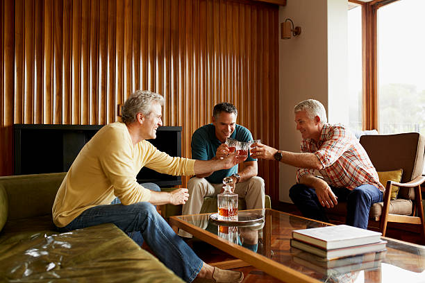 male friends toasting alcohol glasses at home - spirit house стоковые фото и изображения