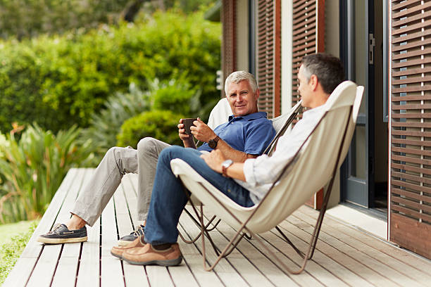 male friends spending leisure time at yard - talking chair two people sitting fotografías e imágenes de stock