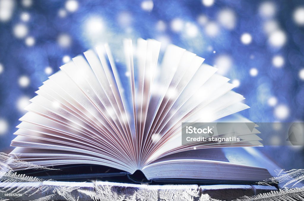 Winter story. Open book on wooden snowy blue background. Winter Stock Photo