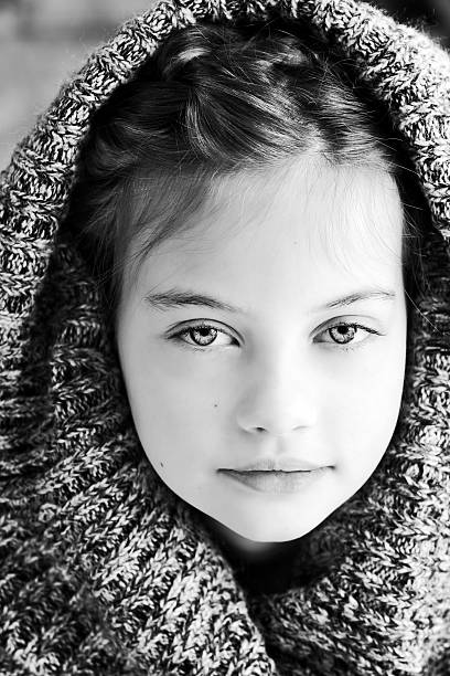 A vintage portrait of a sweet little girl on a cold winter day. The teenager is wearing a fur coat and an ushanka hat. Photo from 1958.