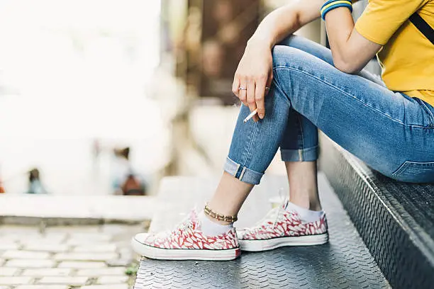 Photo of Depressed teen girl smoking on stairs