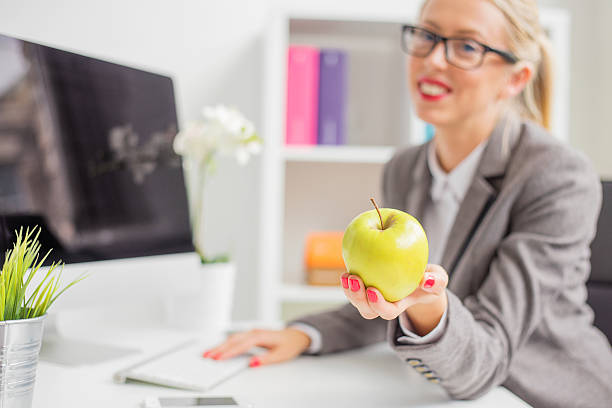 istock Business woman in office holding apple 493530268