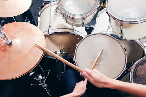 A personal perspective of a woman playing a drum set.