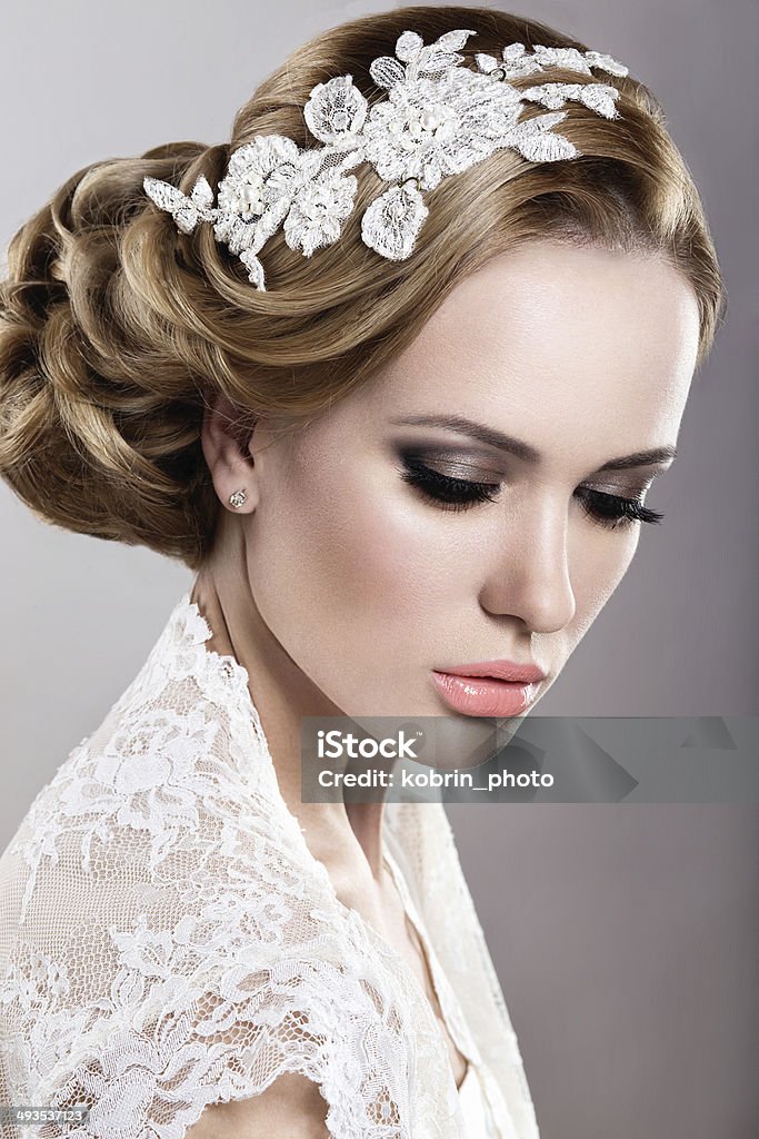 Girl in the image of the bride Portrait of a beautiful blonde woman in a wedding dress in the image of the bride. Picture taken in the studio on a blue background Adult Stock Photo