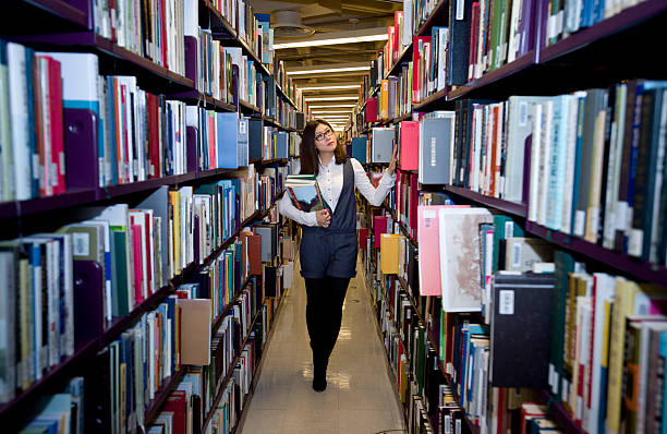 istock Woman reading a book at the library 493539671